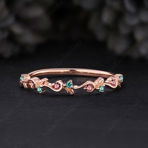 May include: A delicate rose gold band ring with a floral design featuring small pink and green gemstones.