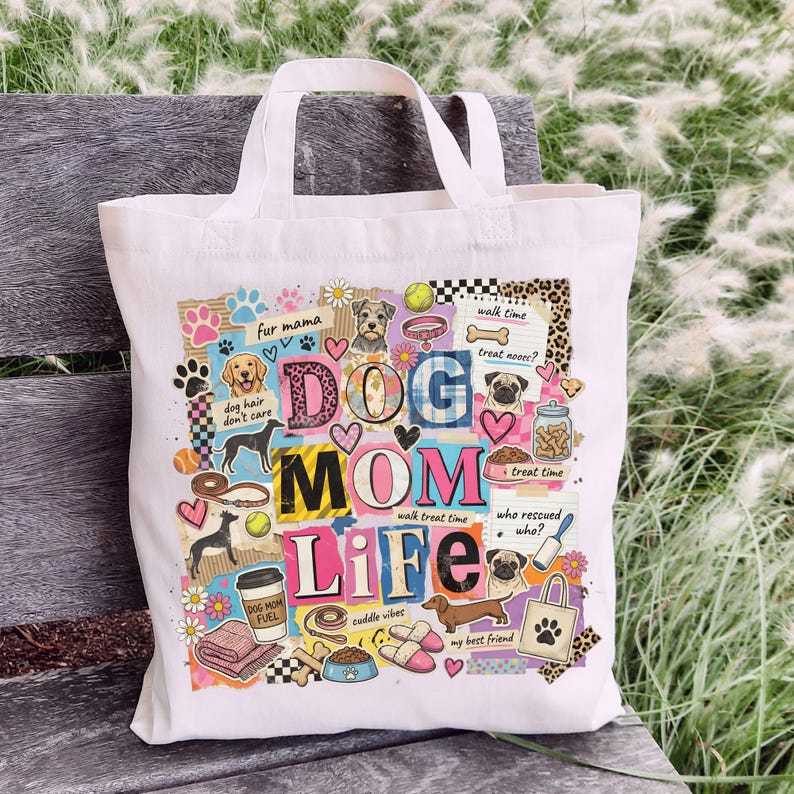 May include: A white canvas tote bag with the words "DOG MOM LIFE" in a colorful collage design. The design includes dog illustrations, paw prints, and phrases like "fur mama" and "walk treat time."