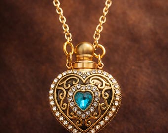 May include: Gold-toned heart-shaped pendant necklace with a blue gemstone center. The pendant is encrusted with clear crystals and features an ornate filigree design. The necklace has a delicate chain and a decorative top.