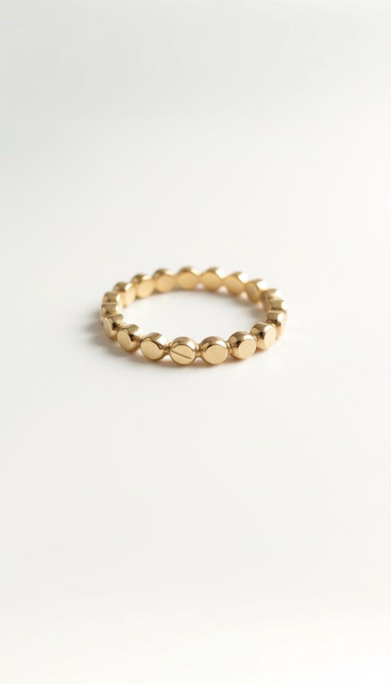 Puede incluir: Un anillo dorado con un dise&ntilde;o de puntos repetidos. El anillo es de metal y tiene un acabado liso y pulido. El anillo mide aproximadamente 1,7 cm de di&aacute;metro.