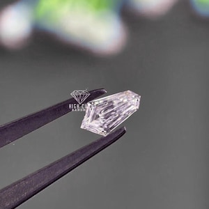 May include: A clear, rectangular-cut diamond held by tweezers. The diamond has multiple facets, reflecting light. The image includes the text "HIGH CARAT HANDMADE" in a diamond-shaped logo.