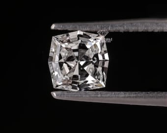 May include: A cushion-cut loose diamond with a brilliant faceted surface, held by metal tweezers against a solid black background. The gemstone displays clear white light reflections and sharp geometric patterns throughout its transparent structure.