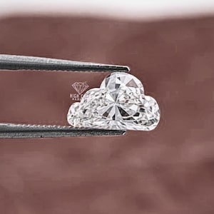 Könnte beinhalten: Ein wolkenförmiger Diamant, der von einer Pinzette gehalten wird. Der Diamant hat viele Facetten, die das Licht reflektieren. Der Hintergrund ist ein gedämpftes Braun. Das Logo "HIGH CLASS HAND" ist sichtbar.