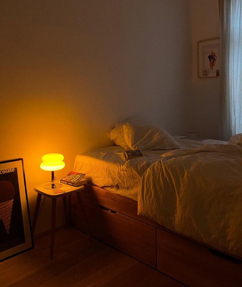Marshmallow Tischlampe in Orange von GLOW UP STUDIO, leuchtet in dunklem Schlafzimmer.