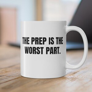 May include: White ceramic coffee mug with black text that reads "THE PREP IS THE WORST PART."