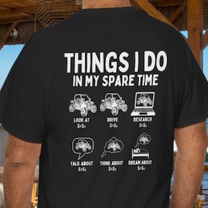 Könnte beinhalten: Schwarzes T-Shirt mit weißem Text und Grafiken. Der Text lautet "THINGS I DO IN MY SPARE TIME" über Illustrationen eines Autos und eines Laptops. Darunter stehen die Sätze "LOOK AT", "DRIVE", "RESEARCH", "TALK ABOUT", "THINK ABOUT" und "DREAM ABOUT".