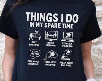 May include: Black t-shirt with white text and graphics about ping pong. The text reads "THINGS I DO IN MY SPARE TIME" with illustrations of playing, watching, researching, talking, thinking, and dreaming about ping pong.