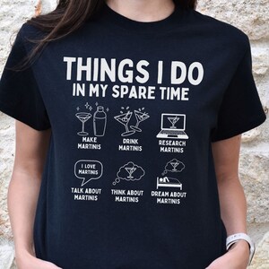 Könnte beinhalten: Schwarzes T-Shirt mit weißem Text, der "Things I do in my spare time" lautet, und einer Liste von Aktivitäten, die mit dem Herstellen und Trinken von Martinis zu tun haben.