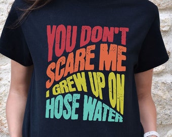 May include: Black t-shirt with a retro-style graphic that reads "You don't scare me I grew up on hose water".