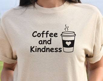 May include: A beige t-shirt with the text "Coffee and Kindness" and a black and white illustration of a coffee cup with a heart on it.