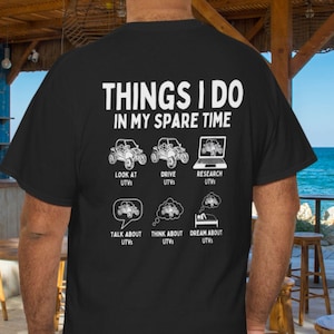 Könnte beinhalten: Schwarzes T-Shirt mit weißem Text und Grafiken. Der Text lautet "THINGS I DO IN MY SPARE TIME" mit Illustrationen von UTVs und verwandten Aktivitäten. Das T-Shirt hat einen Rundhalsausschnitt und kurze Ärmel.