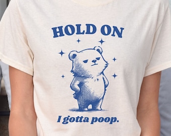 May include: A white t-shirt with a blue illustration of a bear with the text "HOLD ON I gotta poop."
