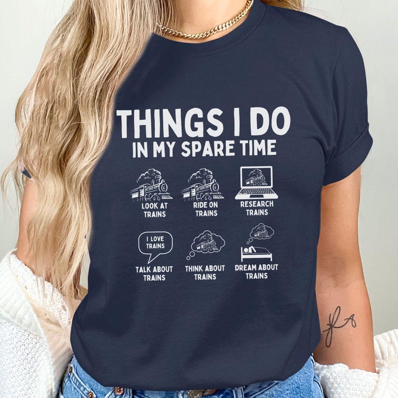 May include: A navy blue t-shirt with the text "Things I do in my spare time" and a series of illustrations of trains. The illustrations depict looking at trains, riding on trains, researching trains, talking about trains, thinking about trains, and dreaming about trains.