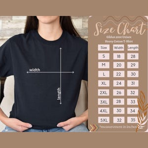 Pode incluir: Uma camiseta preta Gildan 5000 Unisex Heavy Cotton com uma tabela de tamanhos. A tabela lista os tamanhos S a 5XL, com as medidas de largura e comprimento em polegadas. A camiseta &eacute; exibida em uma pessoa.
