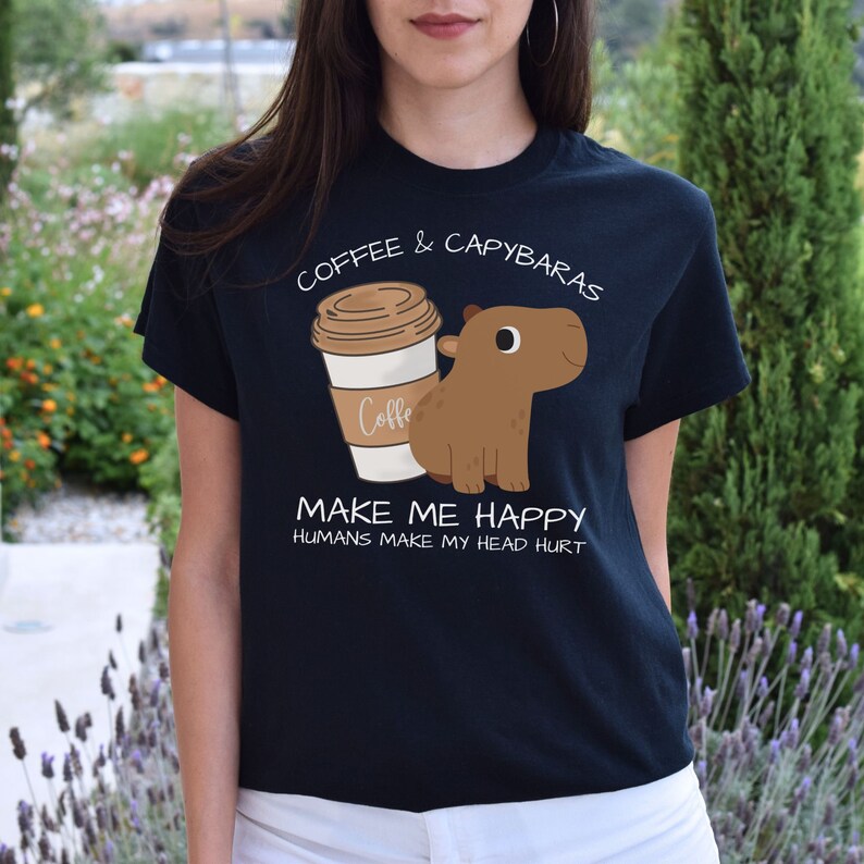 May include: Black t-shirt with a white graphic of a coffee cup and a capybara. The text on the shirt reads "Coffee & Capybaras Make Me Happy Humans Make My Head Hurt."