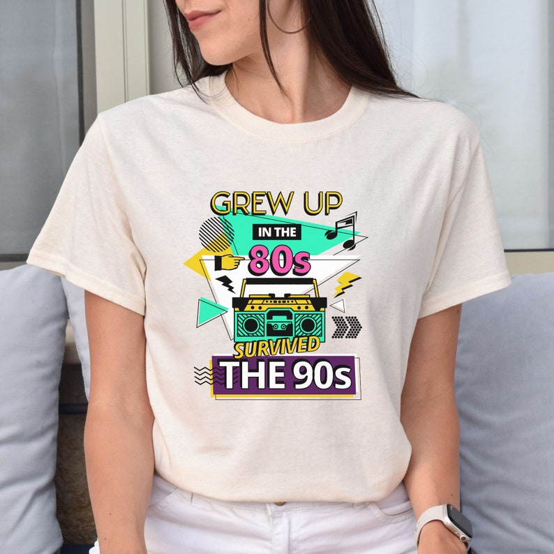 May include: A white t-shirt with a graphic design featuring a boombox, music notes, and the text "Grew Up In The 80s Survived The 90s".