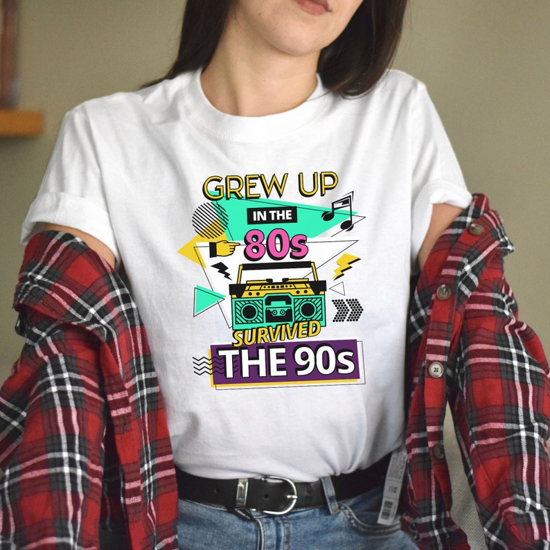 May include: White t-shirt with a graphic design featuring a boombox, the text "Grew Up in the 80s Survived the 90s", and colorful geometric shapes.