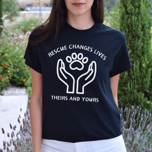 May include: Black t-shirt with a white paw print graphic and the text "Rescue Changes Lives Theirs and Yours".