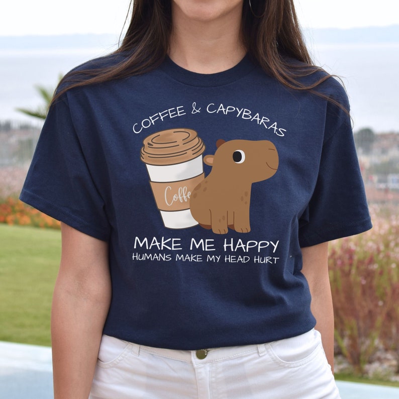 May include: A navy blue t-shirt with a cartoon capybara drinking coffee. The text on the shirt reads "Coffee & Capybaras Make Me Happy Humans Make My Head Hurt."