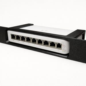 May include: A white network switch with multiple ports, housed in a black rack mount. The switch has several ports and indicator lights. The rack mount has mounting holes on each side.
