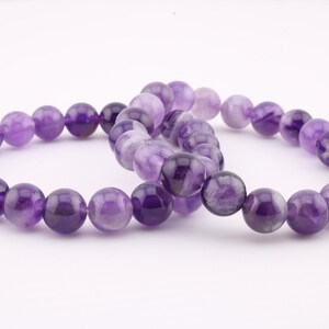 Chevron Amethyst bracelet featuring 8mm and 6mm natural gemstone beads. This women’s jewelry piece promotes calmness, spiritual growth, and intuition. A perfect gift for wellness seekers, offering unique purple and white banded patterns for healing
