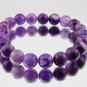 May include: A purple amethyst gemstone bracelet with round beads.