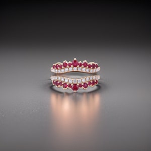 May include: A rose gold ring with a double band design. The top band is set with small round rubies and diamonds, while the bottom band is set with diamonds only. The ring is designed to be worn as a wedding band or engagement ring.