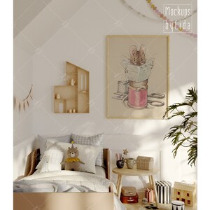 Könnte beinhalten: Ein weißes und graues Kinderbett mit einem braunen Holz-Kopfteil und Fußteil. Das Bett ist mit einer weißen und grauen gemusterten Bettdecke und einem weißen Kissen bezogen. Ein Stofftier in Form eines Bären, der einen Partyhut trägt, sitzt auf dem Bett. Ein gerahmter Druck eines Mause, der in einem Fingerhut mit Schere und Faden sitzt, hängt an der Wand über dem Bett. Ein kleines Holzregal mit Dekoartikeln befindet sich an der Wand links vom Bett. Ein kleiner Tisch mit einer Pflanze und ein paar Dekoartikeln steht rechts vom Bett.