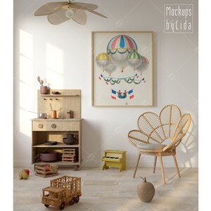 May include: A light wood play kitchen with a wooden toy truck and a yellow toy piano in a room with a white wall and a framed print of hot air balloons with French flags.