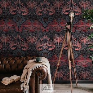 Può includere: Carta da parati grigio scuro con un motivo ripetuto di uccelli rossi stilizzati ed elementi floreali. Un divano in pelle marrone, una coperta e una tazza di caffè sono in primo piano. Una fotocamera e un treppiede vintage sono a destra.