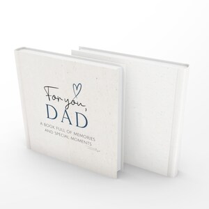 May include: Two off-white hardcover books. The front book cover has the text "For you, DAD" in a mix of script and sans-serif fonts, with a blue heart. Below, it reads "A book full of memories and special moments."