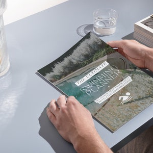 May include: A close-up of a magazine cover with a photo of a swimming pool and the text "The Ultimate Swimming Planner" with the tagline "Set goals, keep track, stay motivated and organized".