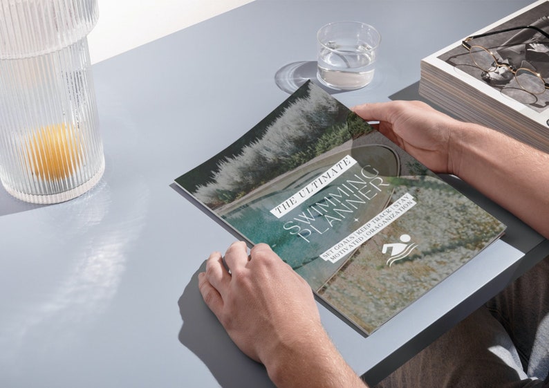 May include: A close-up of a magazine cover with a photo of a swimming pool and the text "The Ultimate Swimming Planner" with the tagline "Set goals, keep track, stay motivated and organized".
