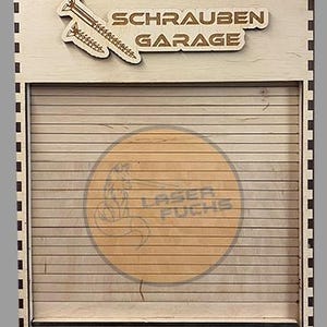 Puede incluir: Letrero de madera con las palabras "SCHRAUBEN GARAGE" y un gráfico de tornillo. El letrero tiene un diseño de listones y un logotipo circular que dice "LASER FUCHS". El letrero está hecho de madera clara.
