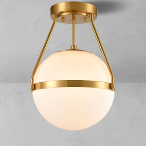 May include: A gold ceiling light fixture with a white globe shade and a brass band around the middle.