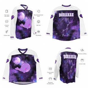 Op de afbeelding: Wit en paars shirt met lange mouwen met een walvisafbeelding en het woord "BORAHAE". De trui heeft een V-hals, afgeronde schouderpas en is gemaakt van ademende, gerecyclede polyesterstof. Inclusief inclusieve maten en unisex stijl.