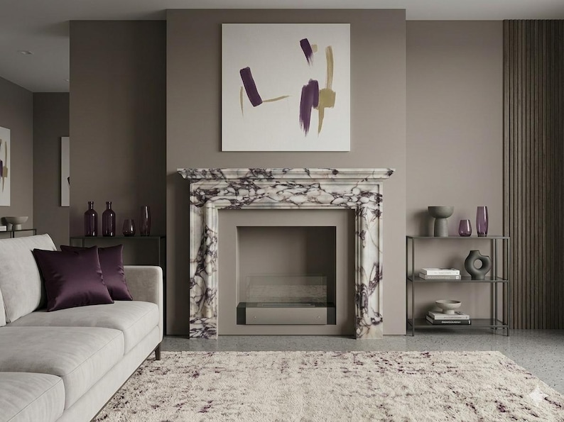 Puede incluir: Una repisa de chimenea hecha de m&aacute;rmol blanco con vetas de color p&uacute;rpura oscuro, con una pintura abstracta cuadrada con pinceladas p&uacute;rpuras y doradas encima, situada en una habitaci&oacute;n con un sof&aacute; gris claro y una alfombra texturizada.