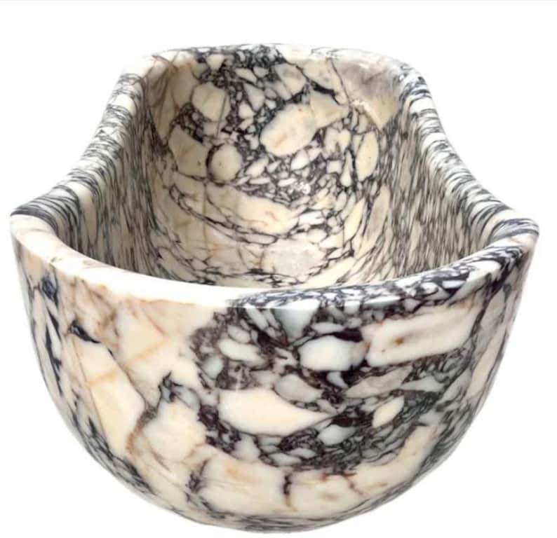 May include: A deep, oval-shaped bowl crafted from polished stone featuring a complex, high-contrast pattern of creamy white, beige, and dark charcoal gray veining throughout the entire exterior and interior surface of the vessel.