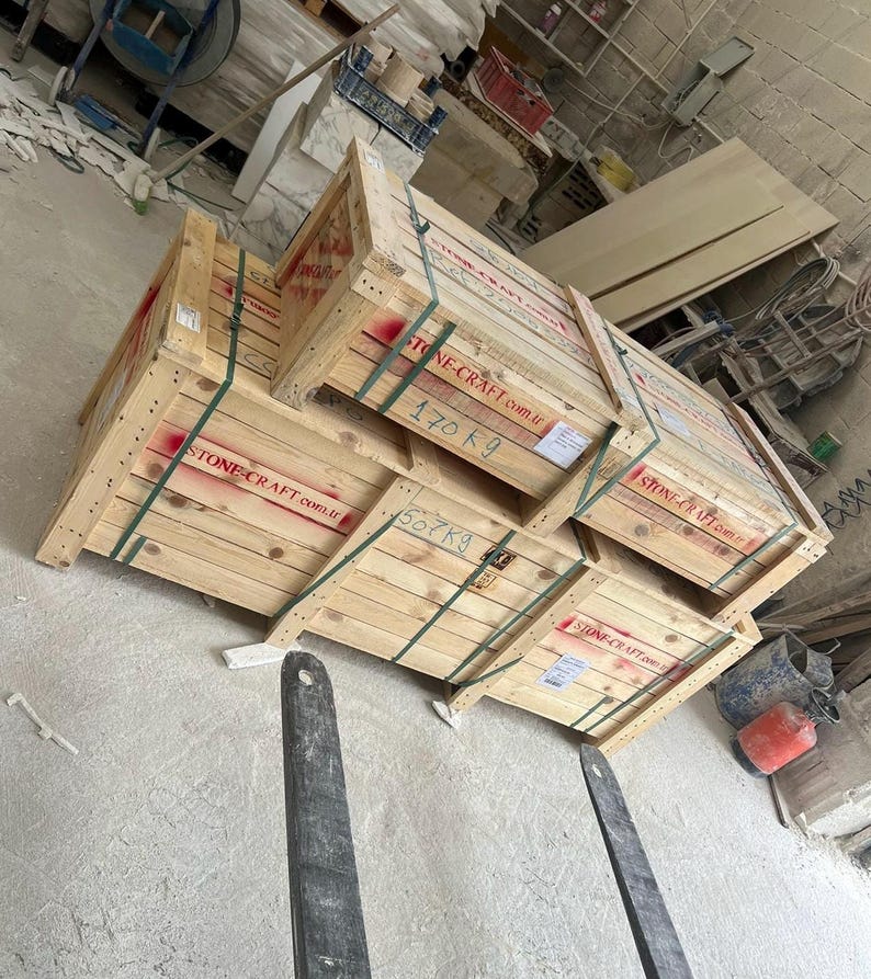 Puede incluir: Tres cajas de env&iacute;o de madera apiladas, construidas con tablones de color claro y aseguradas con correas de pl&aacute;stico verde. Cada caja presenta el texto rojo STONE-CRAFT.com.tr y marcas de peso escritas a mano de 170 kg y 507 kg.