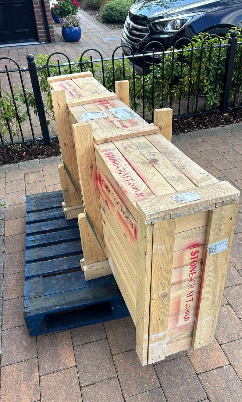 Puede incluir: Una gran caja de env&iacute;o rectangular hecha de tablones de madera clara, con el texto STONE-CRAFT.com.tr estarcido en rojo en el lateral. La caja est&aacute; asegurada con soportes de madera verticales y descansa sobre un pal&eacute; de madera azul.