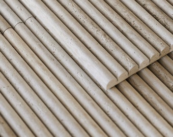 Könnte beinhalten: Nahaufnahme einer Stapelung von hellbeigen, abgerundeten, strukturierten Fliesen. Die Fliesen sind in einem versetzten Muster angeordnet, wodurch ein optischer Rhythmus entsteht.