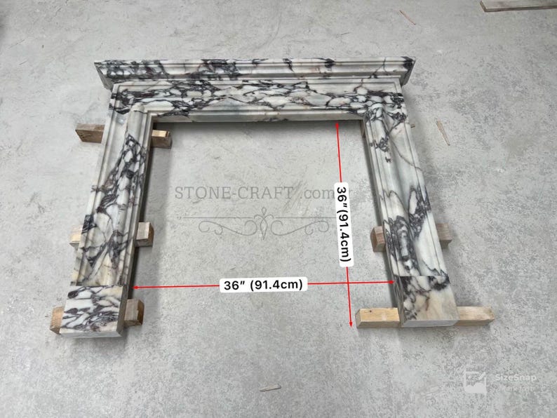 Puede incluir: Una repisa de chimenea de m&aacute;rmol blanco y negro con acabado pulido y vetas complejas. La estructura presenta un estante superior rectangular y dos pilares laterales verticales. Las l&iacute;neas de medici&oacute;n rojas indican 91,4 cm.