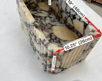 Könnte beinhalten: Ein rechteckiges Steinwaschbecken mit schwarz-weißem Marmormuster und geriffelter Außenseite. Das Waschbecken ist 48 cm lang, 26 cm breit, 14,5 cm tief und 10 cm hoch und verfügt über ein zentrales Abflussloch.