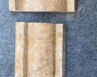 Könnte beinhalten: Drei Travertin-Steinstücke mit einem wellenförmigen, strukturierten Design. Die Stücke sind rechteckig, hellbraun und auf einer grauen Oberfläche angeordnet. Der Stein hat ein natürliches, erdiges Aussehen.