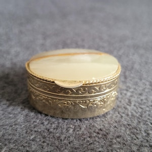 Vintage metal pill box with decorative engraving and lid adorned with natural onyx