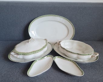 May include: A set of white porcelain serving dishes with green and gold trim. The set includes a large oval platter, two oval serving bowls, and two small oval dishes.