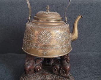 Antike Teekanne aus Metall im orientalischen Stil auf einem kunstvoll geschnitzten Holzständer