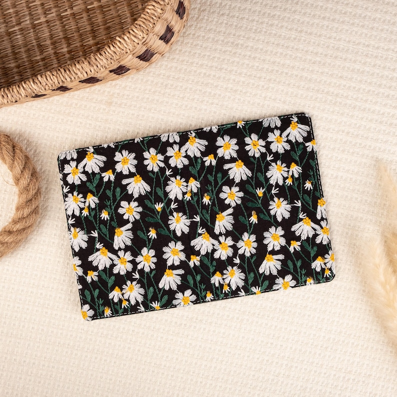 May include: A black clutch with a white daisy floral pattern embroidered on the front.