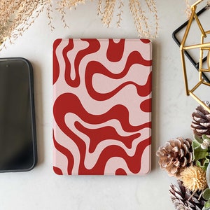 May include: A pink and red abstract swirl pattern Kindle case. The case is made of a soft, textured material.