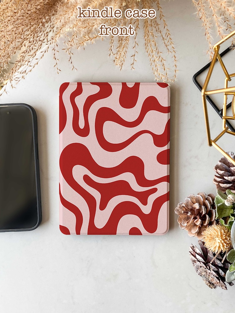 May include: A pink and red abstract swirl pattern Kindle case. The case is made of a soft, textured material.